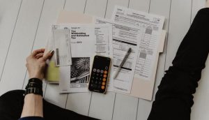 someone working on their taxes. they have papers spread out and a calculator.