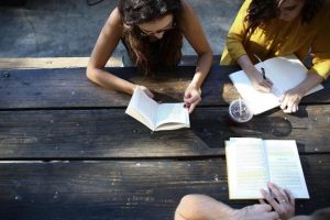 Three people looking over books as part of a book group. Image taken from above.