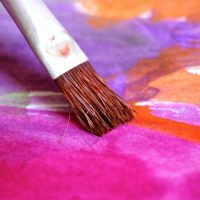 Paintbrush putting pastel colors on a canvas