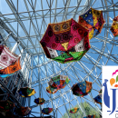 Image of colorful umbrellas hang upside down in the glass conoid of Main Library, with the JLF Colorado logo in the bottom right corner.