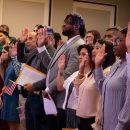 People with their hand raised taking an oath during the citizenship ceremony.