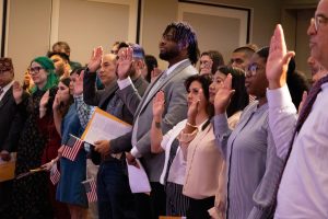 People with their hand raised taking an oath during the citizenship ceremony.