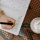 Image of a young person's hand writing in a journal