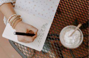 Image of a young person's hand writing in a journal