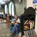 A library staff member reads in front of an antique stove at Reynolds Library.