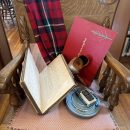 An old wooden chair with a variety of old items on it, including a canister of movie film, an old walkie talkie and a book with long hand writing.